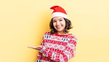 Genç İspanyol kadın neşeyle gülümsüyor, mutlu hissediyor ve bir konsept gösteriyor. Noel konsepti