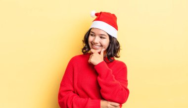 Genç İspanyol kadın mutlu ve kendinden emin bir ifadeyle gülümsüyor. Elleri çenesinde. Noel konsepti