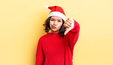 Latin kökenli genç bir kadın kızmış, baş parmağını kaldırmış. Noel konsepti