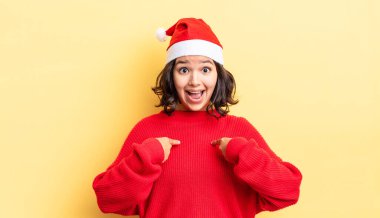 Genç İspanyol kadın kendini mutlu hissediyor ve heyecanla kendini işaret ediyor. Noel konsepti