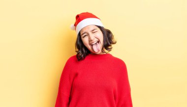 Neşeli ve asi tavırları olan, şaka yapan ve dilini dışarı çıkaran genç İspanyol bir kadın. Noel konsepti