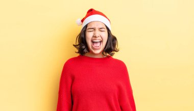 Genç İspanyol kadın agresif bir şekilde bağırıyor, çok kızgın görünüyor. Noel konsepti