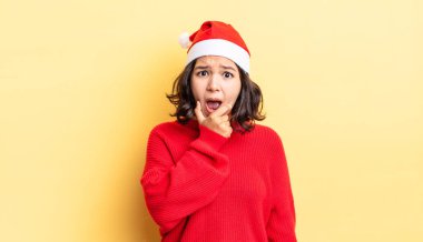 Ağzı ve gözleri sonuna kadar açık ve eli çenesinde olan genç İspanyol kadın. Noel konsepti