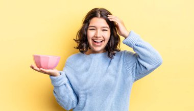 Genç İspanyol kadın mutlu, şaşkın ve şaşırmış görünüyor. boş kase kavramı