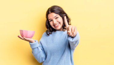 Genç İspanyol kadın gururla gülümsüyor ve kendinden emin bir numara oluyor. boş kase kavramı