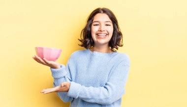 Genç İspanyol kadın neşeyle gülümsüyor, mutlu hissediyor ve bir konsept gösteriyor. boş kase kavramı
