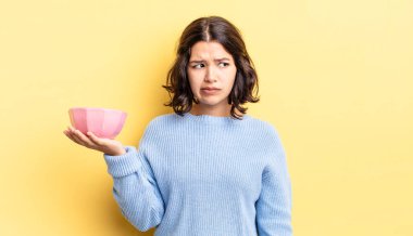 Genç İspanyol kadın üzgün, üzgün ya da kızgın hissediyor ve yana bakıyor. boş kase kavramı