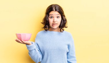 Genç İspanyol kadın şaşkın ve şaşkın görünüyor. boş kase kavramı