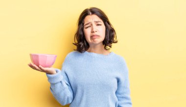 Genç İspanyol kadın üzgün ve mızmızlanıyor. Mutsuz bir bakışı var ve ağlıyor. boş kase kavramı