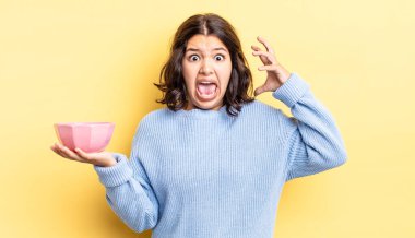 Genç İspanyol kadın ellerini havaya kaldırarak çığlık atıyor. boş kase kavramı