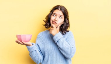 Genç İspanyol kadın düşünüyor, kuşkulu ve şaşkın hissediyor. boş kase kavramı