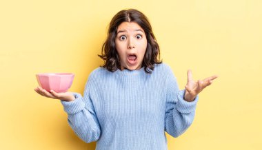 Genç İspanyol kadın şok olmuş ve şaşırmış hissediyor. boş kase kavramı