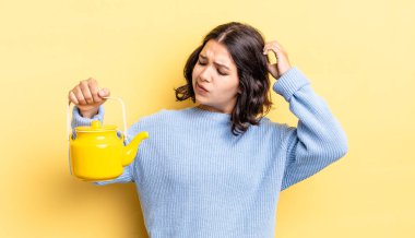 Genç İspanyol kadın mutlu bir şekilde gülümsüyor ve hayal kuruyor ya da şüphe ediyor. çaydanlık konsepti