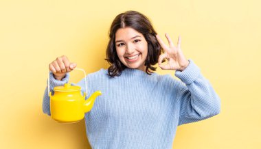 Genç İspanyol kadın kendini mutlu hissediyor, iyi bir jestle onaylıyor. çaydanlık konsepti