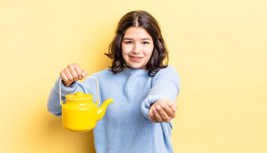 Genç İspanyol kadın mutlu bir şekilde gülümsüyor ve bir konsept sunuyor. çaydanlık konsepti