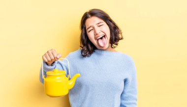 Neşeli ve asi tavırları olan, şaka yapan ve dilini dışarı çıkaran genç İspanyol bir kadın. çaydanlık konsepti