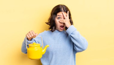 Genç İspanyol bir kadın şok olmuş, korkmuş ya da korkmuş görünüyor. Yüzü elle kapatılmış. çaydanlık konsepti