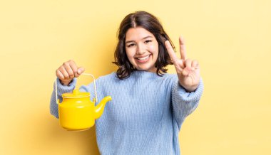 Genç İspanyol kadın gülümsüyor ve arkadaş canlısı görünüyor, iki numarayı gösteriyor. çaydanlık konsepti