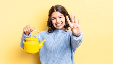 Genç İspanyol kadın gülümsüyor ve arkadaş canlısı görünüyor, dört numarayı gösteriyor. çaydanlık konsepti