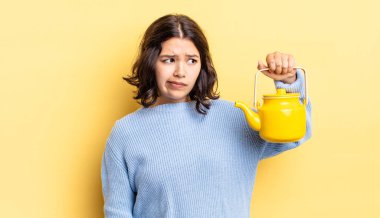 Genç İspanyol kadın üzgün, üzgün ya da kızgın hissediyor ve yana bakıyor. çaydanlık konsepti