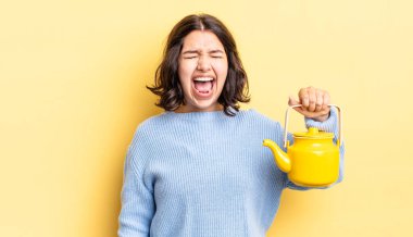 Genç İspanyol kadın agresif bir şekilde bağırıyor, çok kızgın görünüyor. çaydanlık konsepti