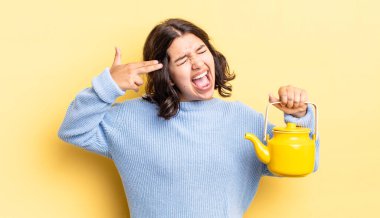 Genç İspanyol kadın mutsuz ve stresli görünüyor, intihar jesti silah işareti yapıyor. çaydanlık konsepti