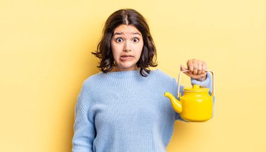 Genç İspanyol kadın şaşkın ve şaşkın görünüyor. çaydanlık konsepti