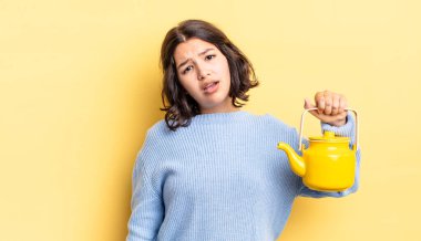 Genç İspanyol kadın şaşkın ve şaşkın hissediyor. çaydanlık konsepti