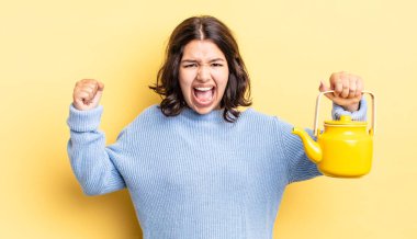 Genç İspanyol kadın öfkeli bir ifadeyle agresif bir şekilde bağırıyor. çaydanlık konsepti