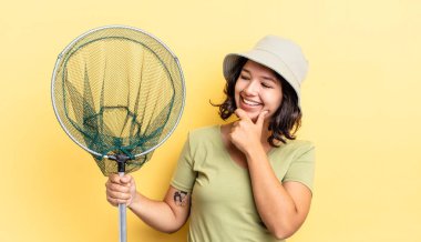 Genç İspanyol kadın mutlu ve kendinden emin bir ifadeyle gülümsüyor. Elleri çenesinde. balıkçı ağı kavramı