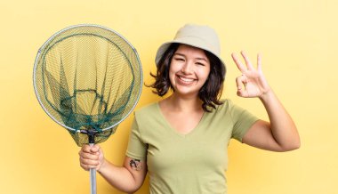 Genç İspanyol kadın kendini mutlu hissediyor, iyi bir jestle onaylıyor. balıkçı ağı kavramı