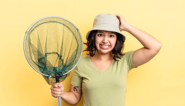 Genç İspanyol kadın stresli, endişeli ya da korkmuş hissediyor, elleri başının üstünde. balıkçı ağı kavramı