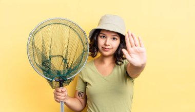 Genç İspanyol kadın ciddi görünüyor. Avuç içini gösteriyor. Durdurma hareketi yapıyor. balıkçı ağı kavramı