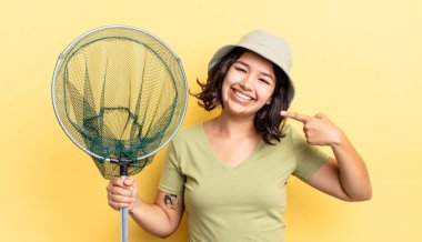 Genç İspanyol kadın kendine güvenerek gülümsüyor ve kendi gülüşünü gösteriyor. balıkçı ağı kavramı