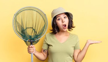 Genç İspanyol kadın şaşırmış ve şok olmuş görünüyor. Çenesi düşmüş ve elinde bir nesne tutuyor. balıkçı ağı kavramı