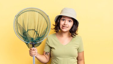 Genç İspanyol kadın şaşkın ve şaşkın görünüyor. balıkçı ağı kavramı