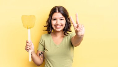 Genç İspanyol kadın gülümsüyor ve arkadaş canlısı görünüyor, iki numarayı gösteriyor. Öldürme konsepti