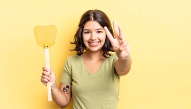 Genç İspanyol kadın gülümsüyor ve arkadaş canlısı görünüyor, üç numarayı gösteriyor. Öldürme konsepti