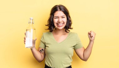 Genç İspanyol kadın şokta, gülüyor ve başarıyı kutluyor. su şişesi kavramı