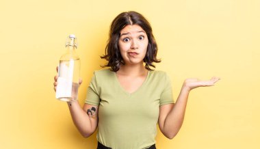 Genç İspanyol kadın şaşkın, şaşkın ve şüpheci hissediyor. su şişesi kavramı