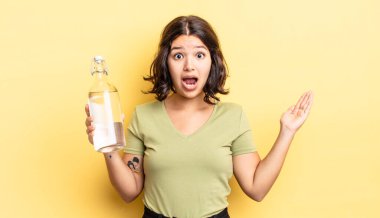 Genç İspanyol kadın kendini mutlu hissediyor ve inanılmaz bir şeye hayret ediyor. su şişesi kavramı