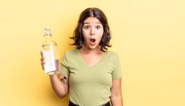 Genç İspanyol kadın çok şaşırmış ya da şok olmuş görünüyor. su şişesi kavramı