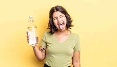 Neşeli ve asi tavırları olan, şaka yapan ve dilini dışarı çıkaran genç İspanyol bir kadın. su şişesi kavramı