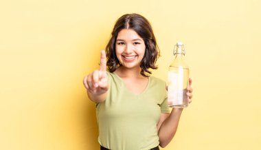 Genç İspanyol kadın gururla gülümsüyor ve kendinden emin bir numara oluyor. su şişesi kavramı