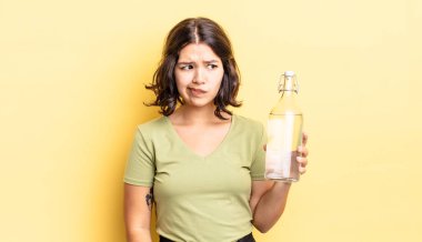 Genç İspanyol kadın üzgün, üzgün ya da kızgın hissediyor ve yana bakıyor. su şişesi kavramı