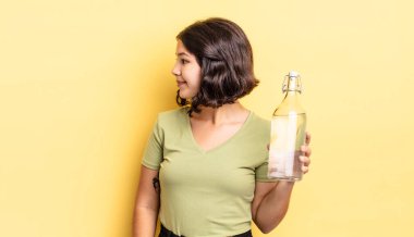 Profil görünümlü genç İspanyol kadın hayal mi kuruyor yoksa hayal mi kuruyor? su şişesi kavramı