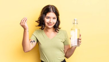 Genç İspanyol kadın kapiş ya da para hareketi yapıyor, sana ödemeni söylüyor. su şişesi kavramı