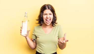 Genç İspanyol kadın kızgın, sinirli ve hayal kırıklığına uğramış görünüyor. su şişesi kavramı