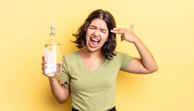 Genç İspanyol kadın mutsuz ve stresli görünüyor, intihar jesti silah işareti yapıyor. su şişesi kavramı