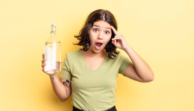 Genç İspanyol kadın şaşırmış görünüyor, yeni bir düşünce, fikir ya da konsept keşfediyor. su şişesi kavramı